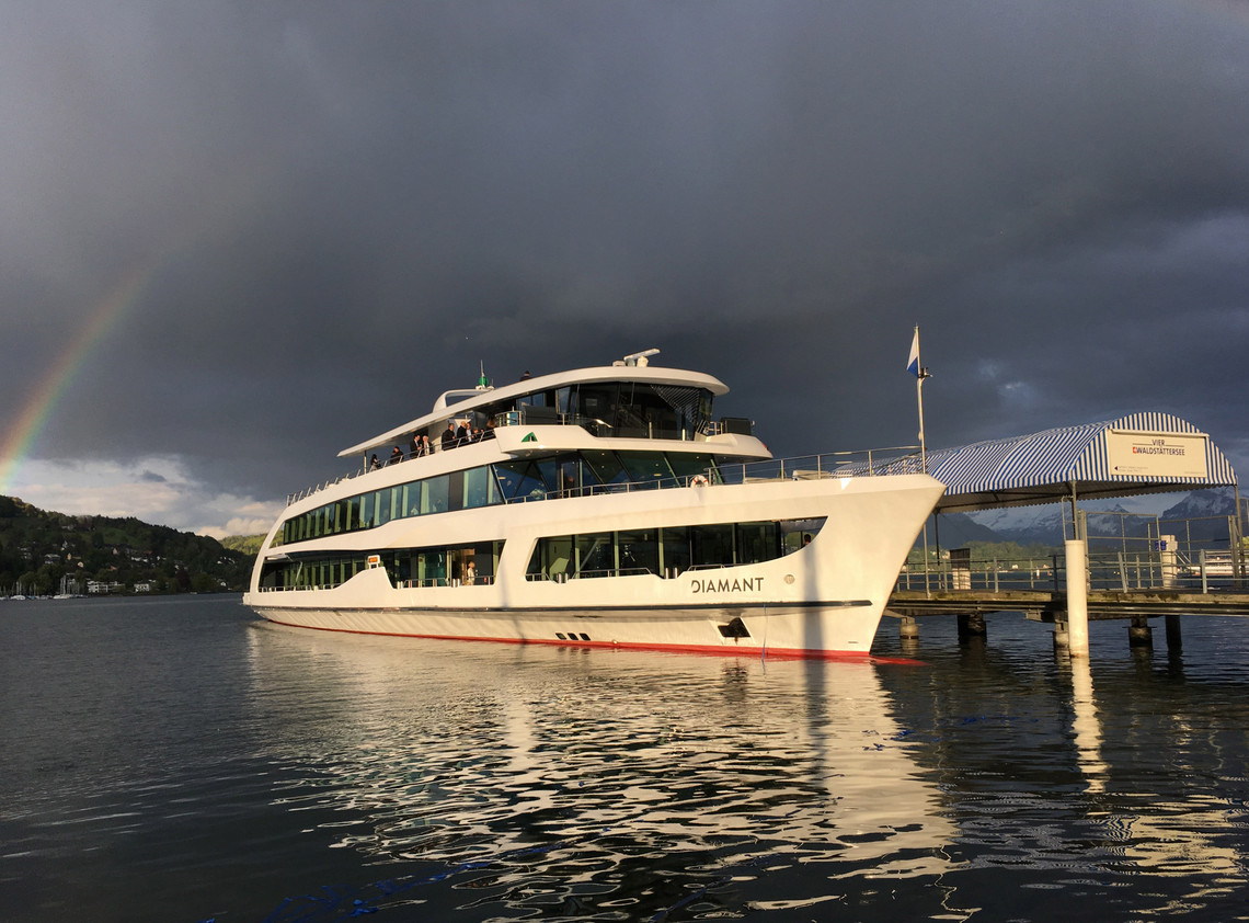 Motorschiff Diamant am Steg Das Motorschiff Diamant schwimmt am Steg in Luzern. Graue Wolken und ein Regenbogen sind im Hintergrund zu sehen.