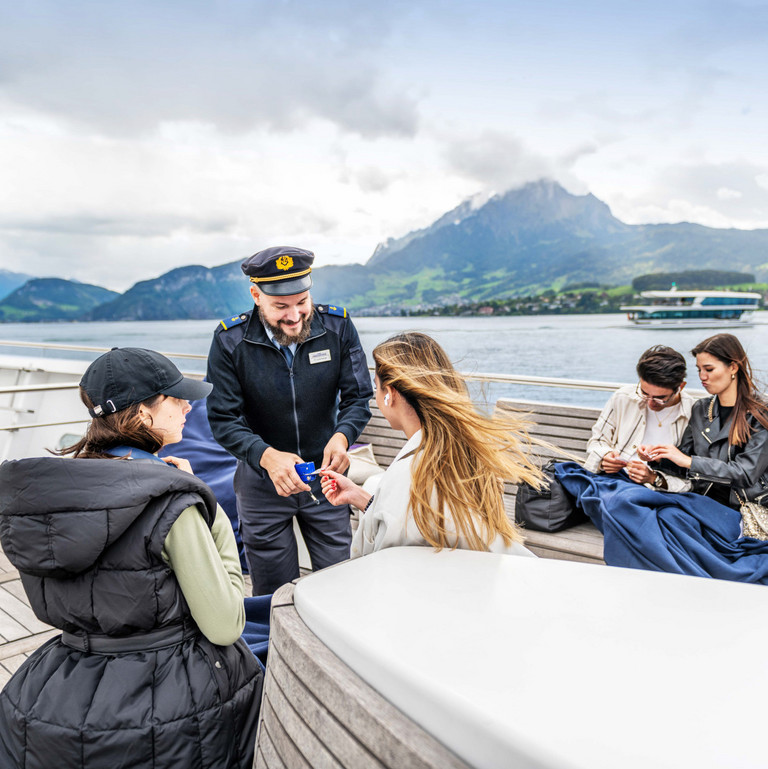 Scenic cruises on the panorama-yacht Saphir - Autumn Guests enjoy an autumn cruise on the motor boat Saphir. The sky is cloudy. In the background you can see the Rigi.
