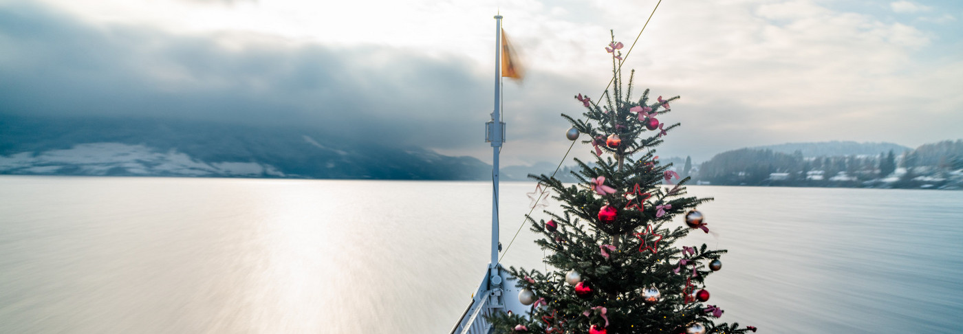 Draussen auf dem Dampfschiff Uri steht ein beleuchteter Weihnachtsbaum.