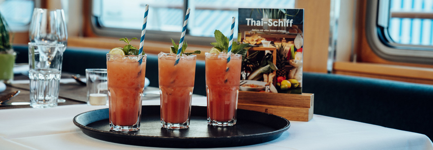 Three cocktails are on a table on the Thai ship.