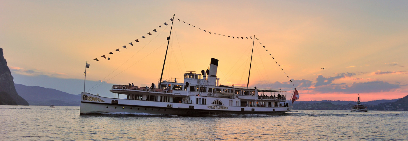 The steamship Stadt Luzern sideways during the trip. The sun sets behind the ship.