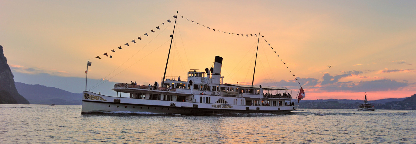 Le bateau à vapeur Stadt Luzern s'écarte latéralement pendant le voyage. Le soleil se couche derrière le navire.