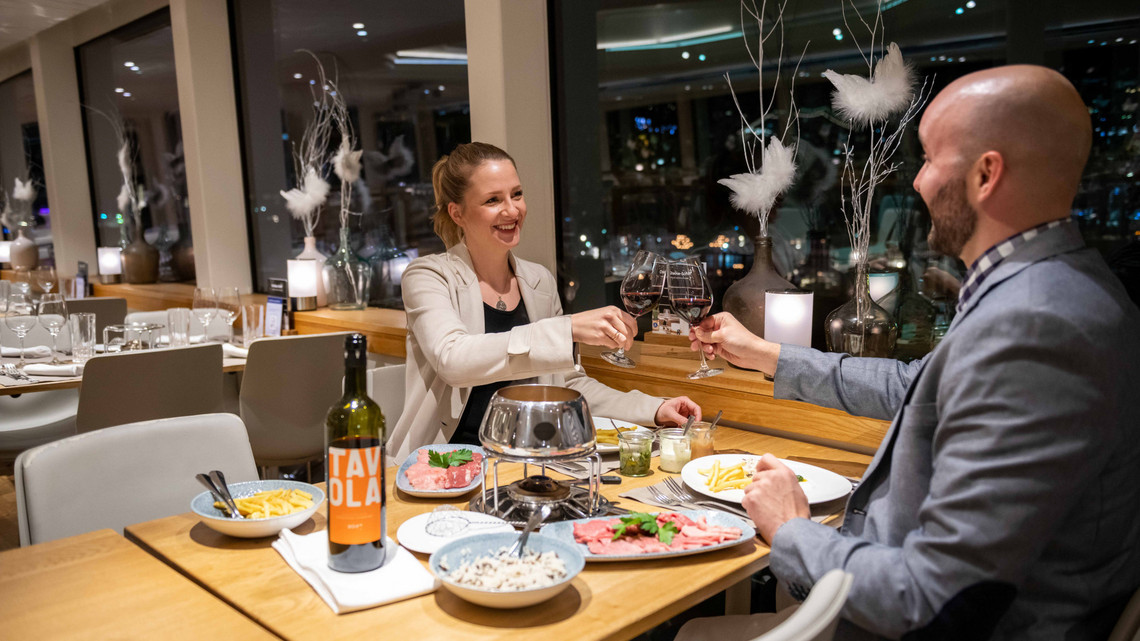 Ein Paar prostet sich zu mit Wein auf dem Fondue Chinoise Schiff