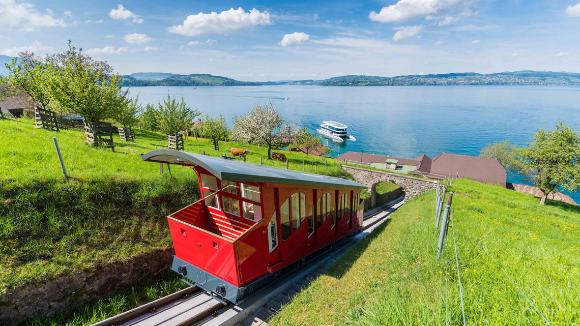 Bateau à moteur Bürgenstock & funiculaire Bürgenstock Le funiculaire rouge du Bürgenstock monte, à l'arrière-plan on peut voir le bateau à moteur du Bürgenstock. C'est une belle journée d'été.