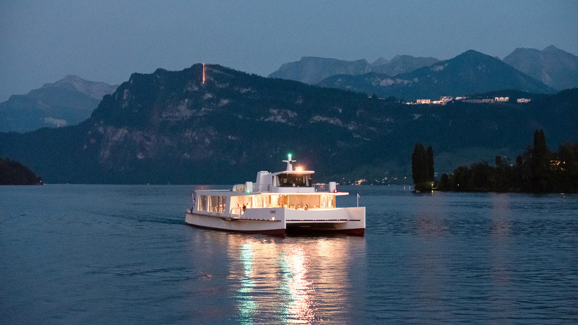 Le bateau à moteur Cirrus lors d'une croisière de fin de soirée Le bateau à moteur Cirrus part tard dans la soirée. Les lumières du bateau se reflètent dans le lac.