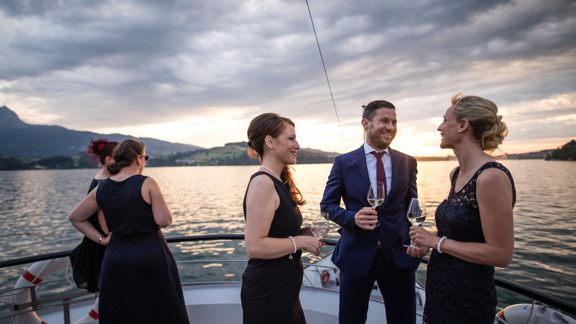 Während einer Schiffsmiete geniesst die festlich gekleidete Gesellschaft einen Apéro draussen auf dem Oberdeck. 