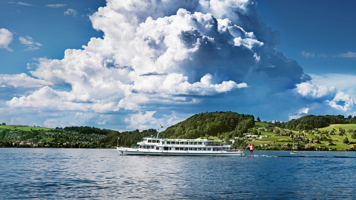 Par une journée ensoleillée, le bateau à moteur Waldstätter passe devant le paysage verdoyant.