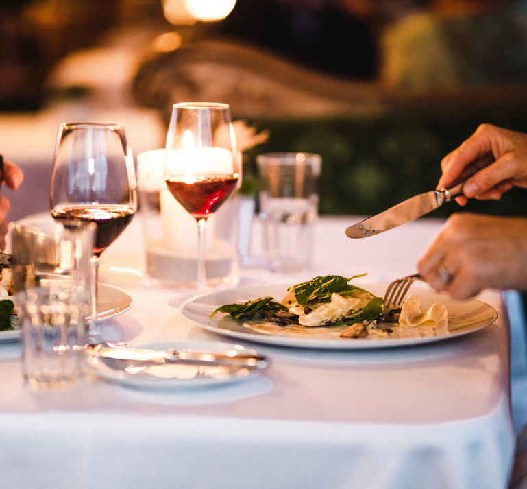 Ein Bild mit einem gedeckten romantischen Tisch mit Rosenblätter für den Valentinstag.