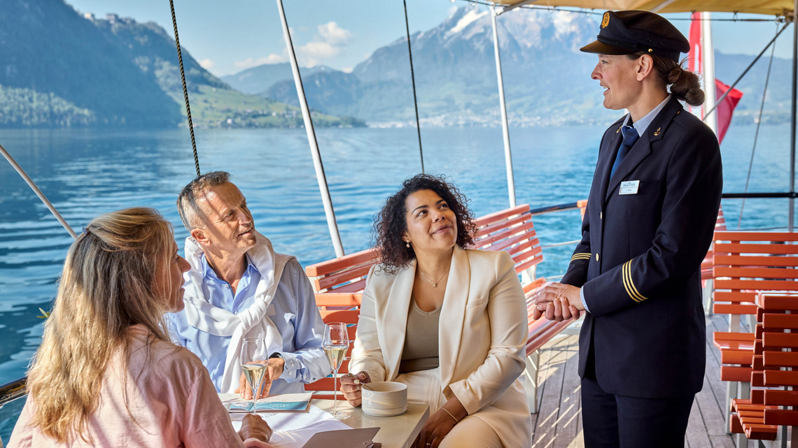 Gespraeche mit der Crew  Die Gäste sitzen draussen auf dem Dampfschiff und sprechen mit der Bordcrew.