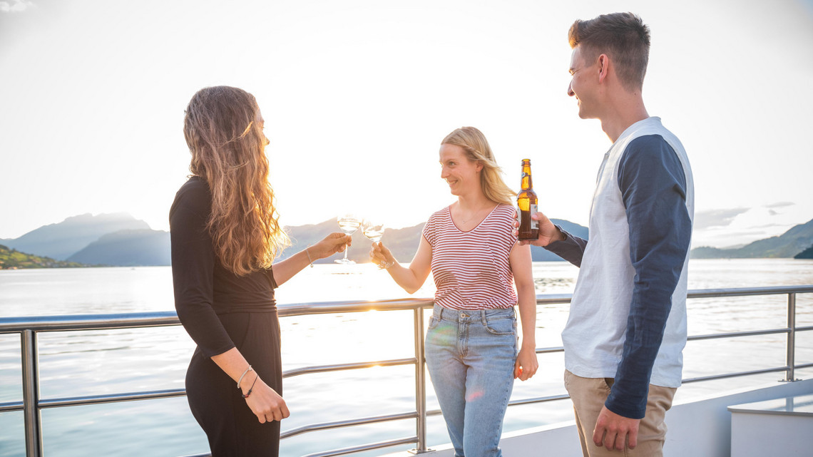 Sonnenuntergang auf dem Schiff. Menschen stossen mit Drinks an