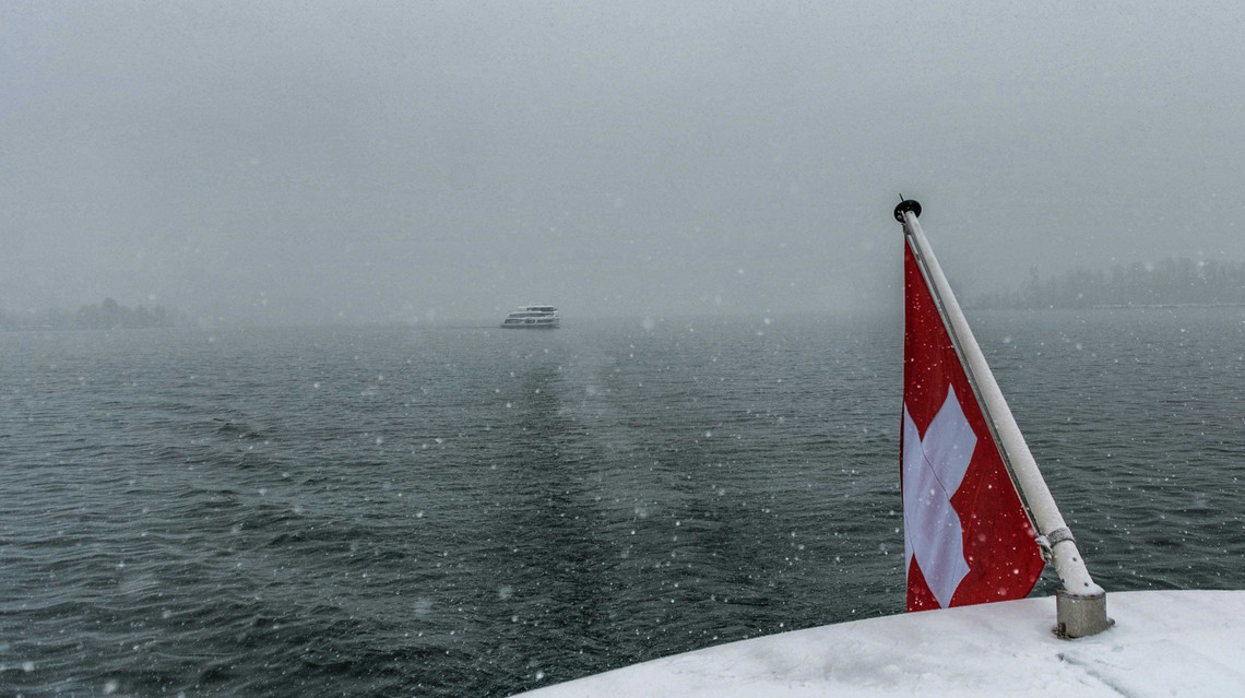 Es schneit Die rote Schweizerfahne wird verschneit