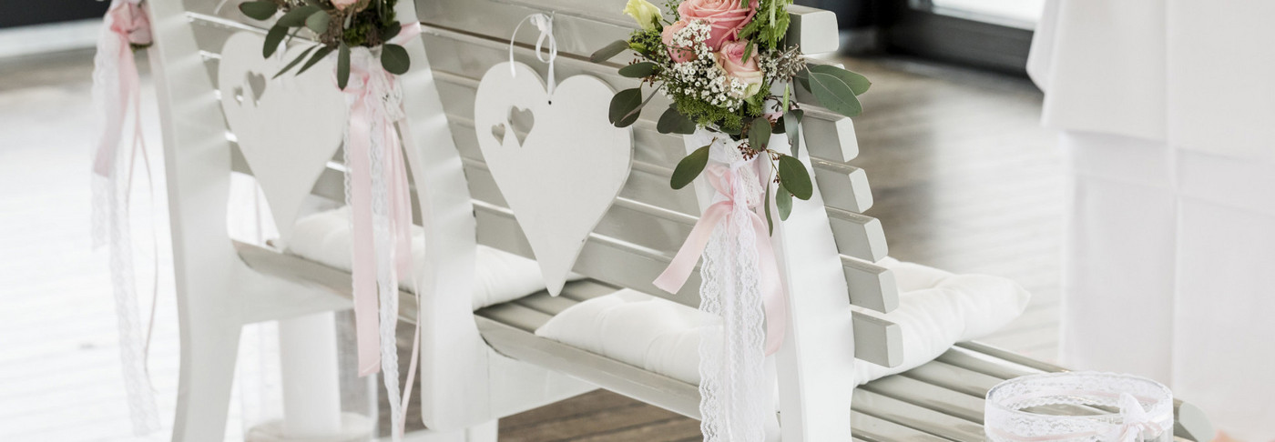 Wedding bench decorated with roses in front of the wedding altar on a ship.