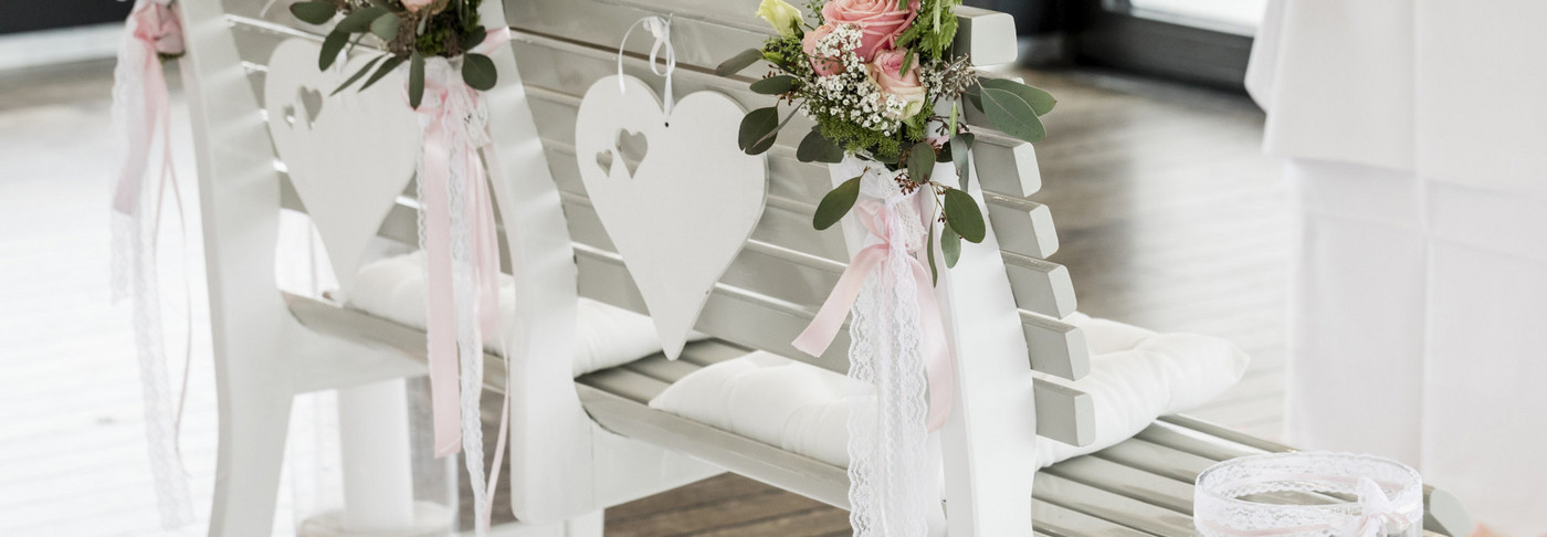 Hochzeitsbank dekoriert mit Rosen vor dem Trauungs-Altar auf dem Schiff.
