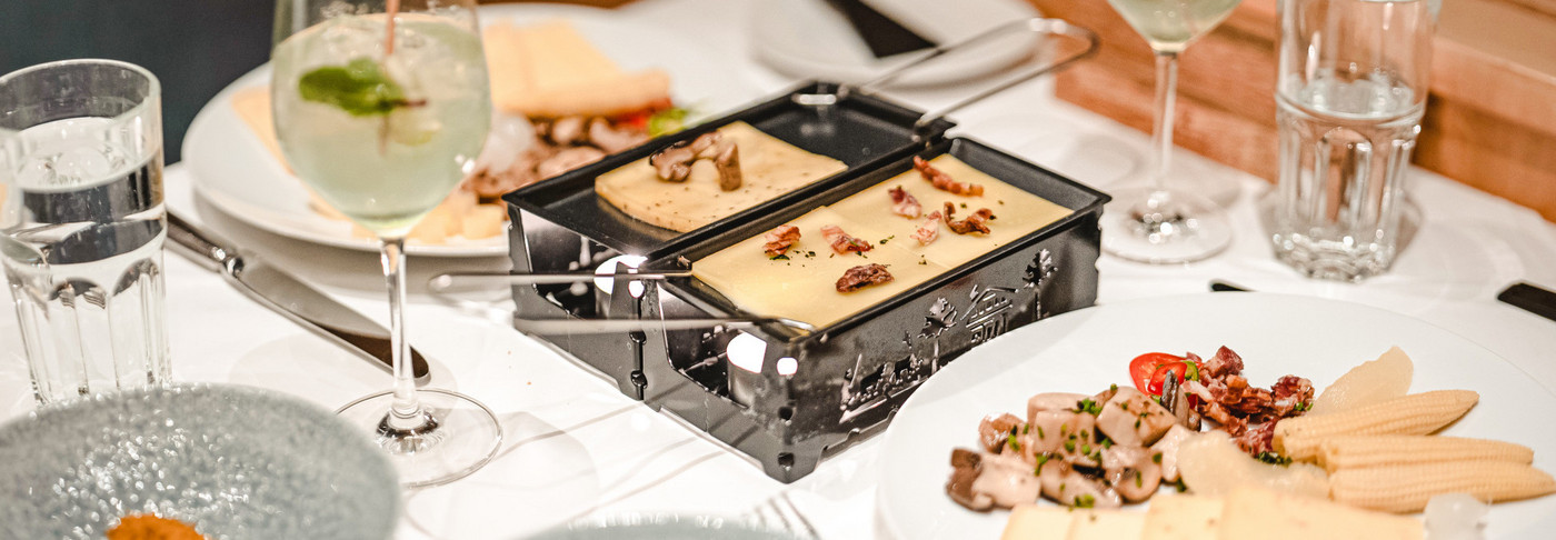 Manger une raclette sur un bateau à moteur. On peut voir la table dressée avec le four à raclette et le fromage.