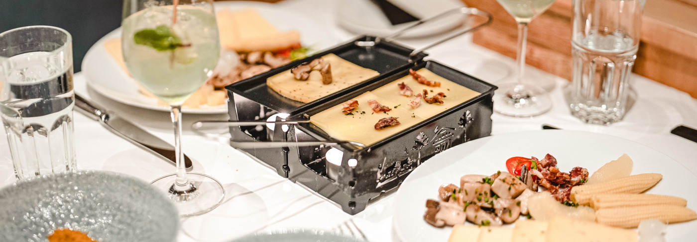 Manger une raclette sur un bateau à moteur. On peut voir la table dressée avec le four à raclette et le fromage.
