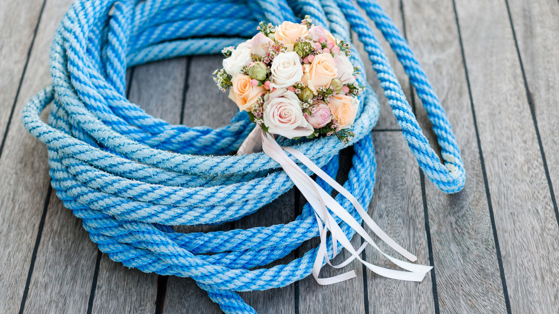 Schiffsmiete Hochzeitsfeier - Brautstrauss Nahaufnahme von einem Brautstrauss mit hellen Rosen auf einem blauen Tau.