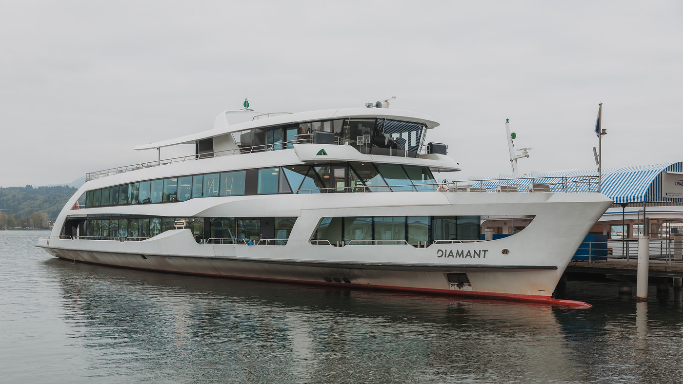 Das Motorschiff Diamant fährt an einem schönen Sommertag voll beladen mit glücklichen Gästen auf dem Vierwaldstättersee. 