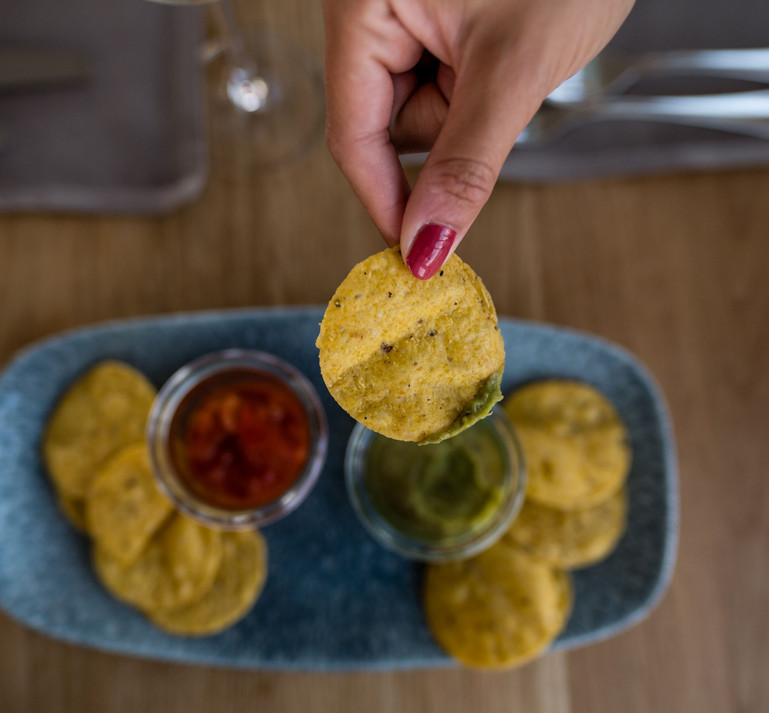 Apero Dip mit Chips und Saucen. Hand hält die Chips