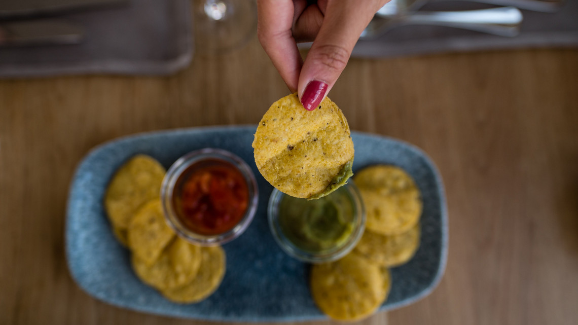 Dip mit mexikanischen Saucen zum Apero Apero Dip mit Chips und Saucen. Hand hält die Chips